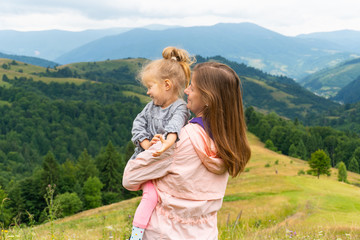 Mom holding her little child girl with mountain view behind