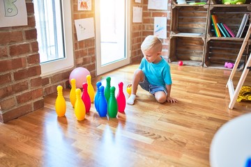 Fototapeta premium Young caucasian kid playing at kindergarten with toys. Preschooler boy happy at playroom.