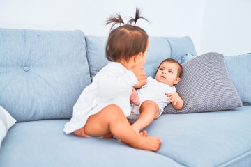 Beautiful infant happy girls playing together at home kindergarten sitting on the sofa