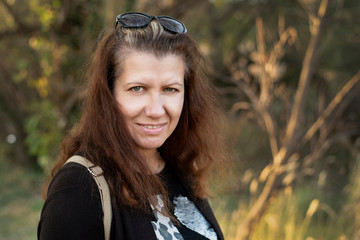 Portrait of middle-aged woman in nature, woman smiling and rejoicing taking time to rest from noise...