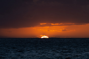 Fototapeta na wymiar Beautiful sunset with sun touching the horizon of ocean in Hawaii