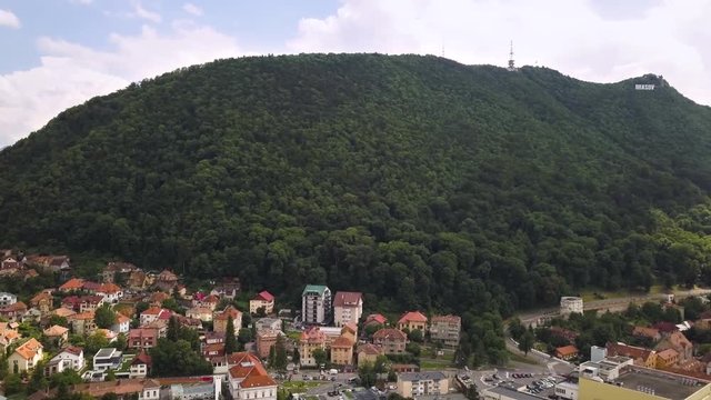 Aerial view of Brasov city, medieval town situated in Transylvania, Romania. Old architecture surrounded with big Carpathian mountains covered with dense green forest.