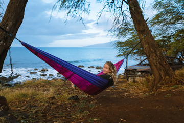 Young woman in hammock on remote beach on beautiful sunny day in Maui, Hawaii