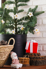 Christmas interior. The wooden windowsill is decorated with a Christmas tree, a wicker basket with cones and Christmas tree toys and garland lights