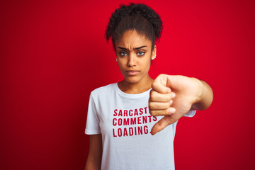 Afro american woman wearing funny t-shirt with irony comments over isolated red background with...