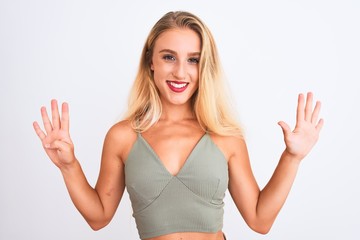 Young beautiful woman wearing casual green t-shirt standing over isolated white background showing and pointing up with fingers number nine while smiling confident and happy.