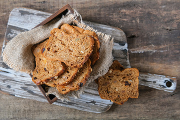 Pieces of rye whole grain bread with pieces of prunes and dried apricots on the kitchen cutting board.