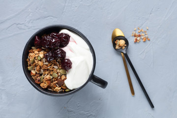 Granola with homemade yogurt and cherry jam on grey table, flat lay