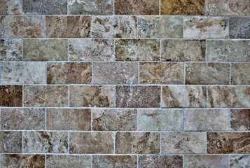 Brown colors on large bricks layered on a building exterior. Rough texture with earth tones.
