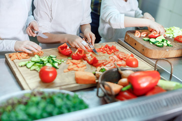 Children grind vegetables in the kitchen.