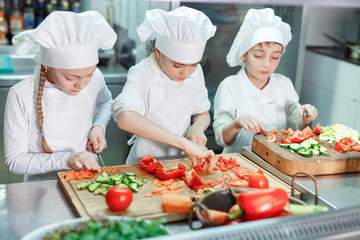 Children grind vegetables in the kitchen.