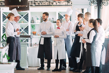 Restaurant manager and his staff in terrace. interacting to head chef in restaurant.