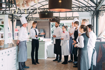 Restaurant manager and his staff in terrace. interacting to head chef in restaurant.