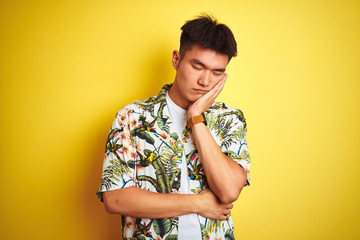 Asian chinese man on holiday wearing summer shirt over isolated yellow background thinking looking tired and bored with depression problems with crossed arms.