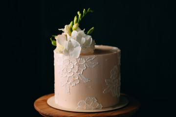 Cake is decorated with flowers on a dark background.