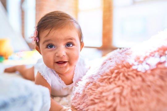 Beautiful infant happy at kindergarten around colorful toys lying on blacket
