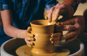 Fototapeta na wymiar Pottery workshop. Grandpa teaches granddaughter pottery. Clay modeling