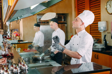 The chef prepares food in front of the visitors in the restaurant