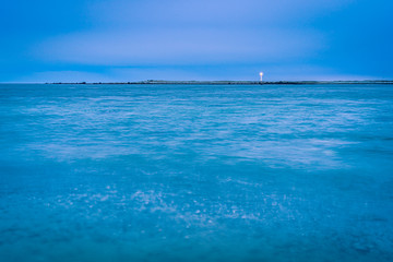 Fototapeta premium Lighthouse seascape smooths out the ocean surface while the light shines with long exposure.