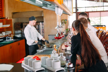 The chef prepares food in front of the visitors in the restaurant