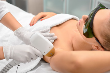 Hair removal cosmetology procedure from a therapist at cosmetic beauty spa clinic. Laser epilation underarm.