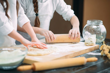 Obraz na płótnie Canvas funny girls kids are preparing the dough in the kitchen.