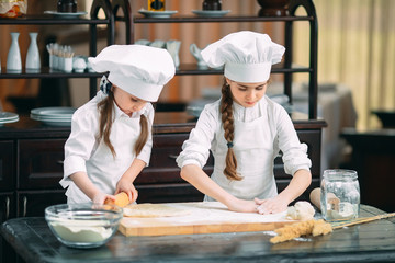 funny girls kids are preparing the dough in the kitchen.