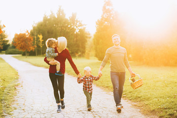 Photo of cheerful family walking in park on sunset for picnic
