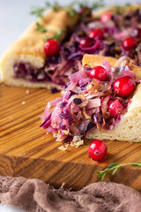 Homemade open pie with different types of cabbage, sauerkraut and cranberry on wooden cutting board. Selective focus. Vegetarian food.