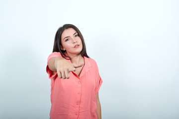 Young woman on white background frustrated by a bad situation and pointing to the front. Points the index finger forward at an object or direction