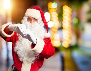 Middle age handsome man wearing Santa Claus costume and beard standing smiling in love doing heart symbol shape with hands. Romantic concept.