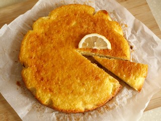 Top view photo of a freshly baked lemon cake with one slice cut, lying on a baking paper and a...