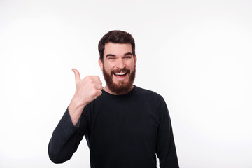 DONE ! Cheerful bearded man, freelancer showing thumb up and smiling at camera over isoalted...