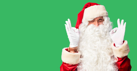 Middle age handsome man wearing Santa Claus costume and beard standing relaxed and smiling with eyes closed doing meditation gesture with fingers. Yoga concept.
