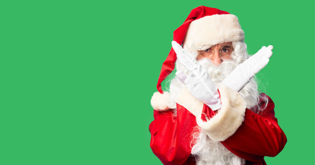 Middle age handsome man wearing Santa Claus costume and beard standing Rejection expression crossing arms doing negative sign, angry face