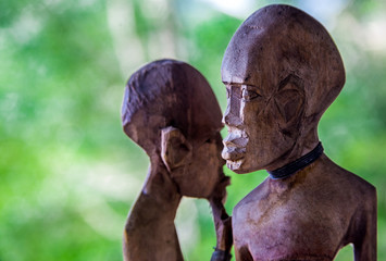 dramatic image of carved wooden figures of a African man and woman with blurred background