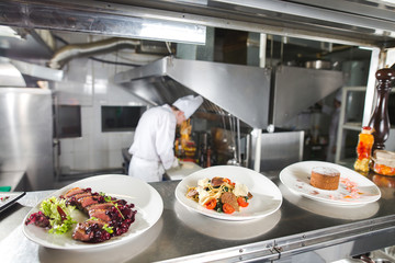 the distribution table in the kitchen of the restaurant. the chef prepares a meal on the background of the finished dishes.