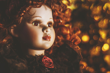 Porcelanowa lalka w blasku świątecznych świateł. 