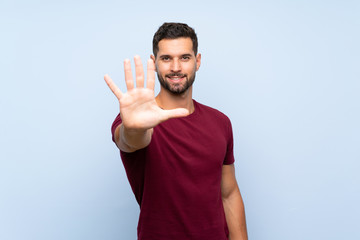 Fototapeta premium Handsome man over isolated blue background counting five with fingers