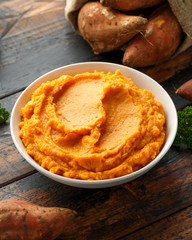Mashed Sweet Potatoes in white bowl on wooden rustic table. Healthy food