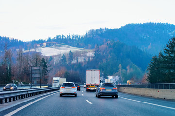 Car traffic on road. Auto vehicle on driveway. European transport lon driveway. Automobiles and truck on highway. Scenery on background. Slovenia or Austria