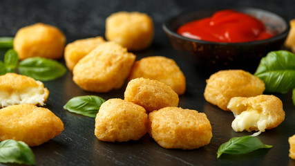 Fried mozzarella, cheddar cheese bites, balls with ketchup on rustic stone board