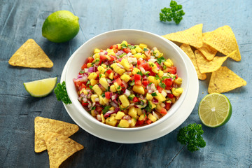 Bowl of fresh Mango Salsa with nachos chips and herbs. Healthy Vegan, Vegetables food.