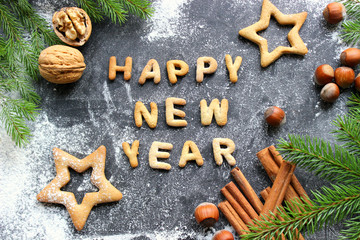 Baked letters Happy New year, stars, snowflakes.Greeting card with gingerbread.Christmas card made of gingerbread on a wooden table surrounded by fir branches, nuts, spices and orange. Rustic style, c