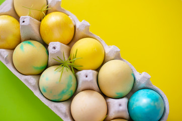 Colored blue and yellow Easter eggs in egg box on colorful background. Traditional Christian eastertime.