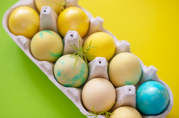 Fototapeta na wymiar Colored blue and yellow Easter eggs in egg box on colorful background. Traditional Christian eastertime.