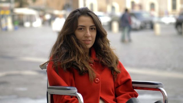 happy beautiful woman on wheelchair smiling at camera in the city