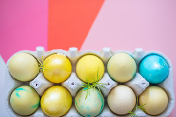 Colored blue and yellow Easter eggs in egg box on colorful background. Traditional Christian eastertime.