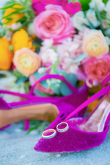wedding rings on purple shoes in sand with flowers