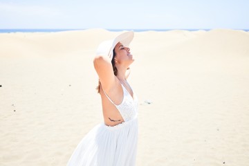 Fototapeta na wymiar Young beautiful woman sunbathing with open arms enjoying summer vacation at maspalomas dunes beach
